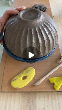 a person is making a vase out of clay on a cutting board with scissors and other tools