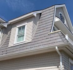 a house with a clock on the side of it's face and windows in the roof