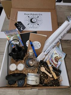 an open box filled with items from the moon ritual kit on top of a wooden table