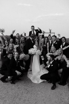 a group of people posing for a photo with their arms in the air and holding bouquets