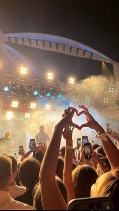 people are holding up their cell phones to take pictures at a concert with the lights on