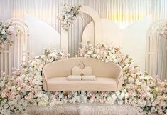 a white couch sitting in front of a flower covered wall with two hearts on it