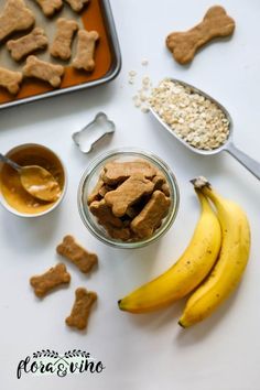 dog treats and peanut butter are on the table next to bananas, oatmeal, and cookie cutters