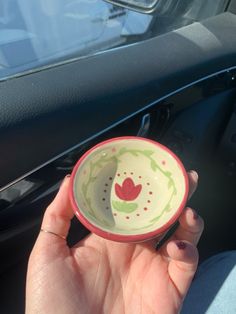 a hand holding a small bowl in front of a car door with the handle down