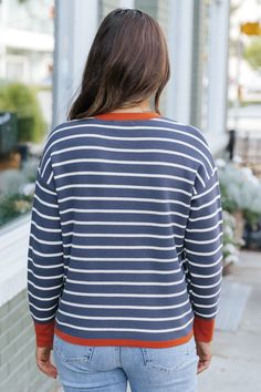 Upgrade your fall wardrobe with our Navy Stripe Contrast Sweater! This stylish and versatile piece features a subtle orange contrast detail at the neckline and cuffs, adding a pop of color to your outfit. Made with a comfortable crew neckline, stay cozy and chic all season long. Style with your favorite denim jeans, sneakers, and simple accessories for a chic everyday outfit. Orange Color Block Tops For Fall, Casual Tops With Striped Cuffs For Fall, Fall Tops With Striped Cuffs And Relaxed Fit, Fall Orange Color Block Tops, Orange Crew Neck Top For Layering, Orange Color Block Crew Neck Sweater, Casual Fall Tops With Striped Hem, Orange Ribbed Cuffs Sweatshirt For Fall, Navy Tops For Everyday Fall Wear