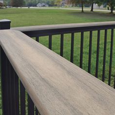 a wooden bench sitting on top of a metal rail next to a lush green field