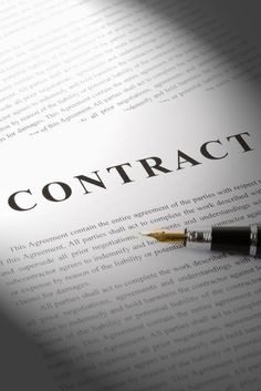 a pen sitting on top of a paper with the word contract in black and white