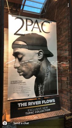 the poster for 2pac's upcoming album is hanging in front of a brick wall