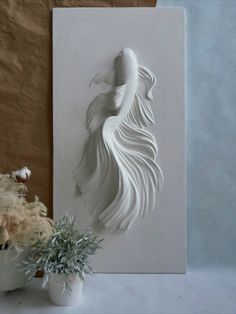 a white sculpture sitting on top of a table next to a potted plant