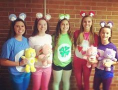 four girls are holding stuffed animals in front of a brick wall