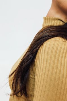 a woman with long brown hair is wearing a yellow shirt and holding a cell phone to her ear