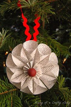 an ornament made out of book pages hanging from a christmas tree with red ribbon