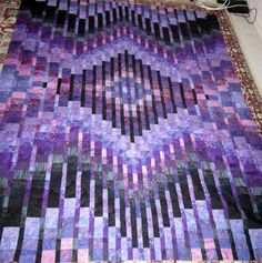 a purple and black quilt sitting on top of a rug