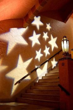 the shadows of stars cast on stairs in front of a wall with a light fixture