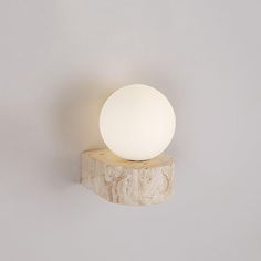 a white ball sitting on top of a wooden block next to a wall mounted light