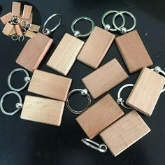 several square wooden key chains are on a table with other wood pieces and metal rings