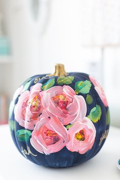 a painted pumpkin sitting on top of a table next to a plate with pink flowers