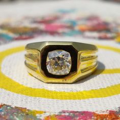 a close up of a ring with a diamond in the center on a table cloth