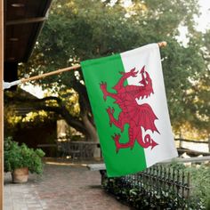 a green and white flag with a red dragon on it is hanging from a pole