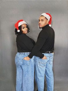 two people wearing christmas hats standing next to each other