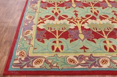 a red and blue rug with flowers on the floor in front of a wooden floor