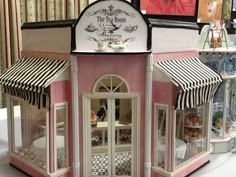 the doll house is pink and white with striped awnings