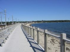 a long walkway next to the ocean on a sunny day with no people in it