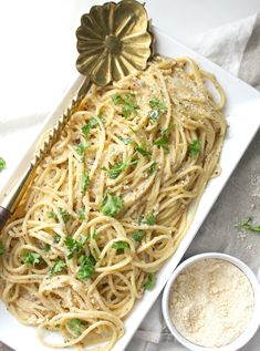 a white plate topped with pasta and parsley next to a bowl of seasoning