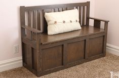 a wooden bench with a white pillow on it's back and some drawers underneath