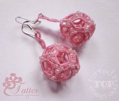 two pink beads are attached to silver earwires on a white surface with the words tater written below them