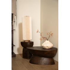 a wooden table with two vases on top of it next to a white wall