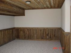 an empty room with wood paneling on the ceiling and carpeted floor is shown