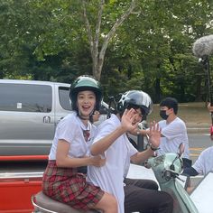 two people riding on the back of a moped