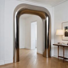 a large metal arch in the middle of a room next to a table with a lamp on it