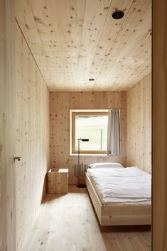 a bedroom with wood paneling and a bed in the corner next to a window