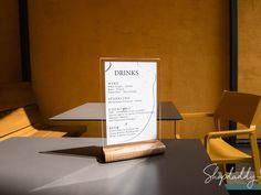 a menu sitting on top of a table next to a yellow chair in front of a brown wall