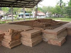 several pieces of wood stacked on top of each other under a covered area with trees in the background