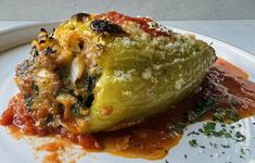 an eggplant stuffed with cheese and tomato sauce on a white plate, ready to be eaten