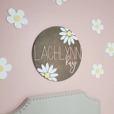 a sign that says laclynnn bay on the wall above a bed with daisies