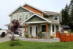 a house that is in the grass with trees and bushes around it's front yard