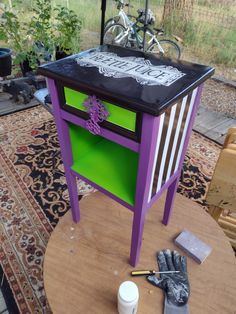 a purple and green table with some paint next to a bike on top of it