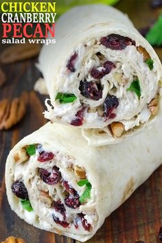 two wraps filled with chicken, cranberries and pecans on top of a wooden table