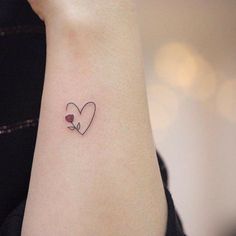 a woman's wrist with a small heart and flower tattoo on her left arm