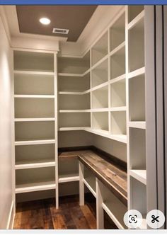 an empty walk in closet with white shelving and wood flooring on the walls