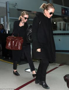 two women are walking through an airport with their handbags in each other's pockets