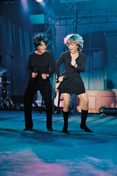 two women are performing on stage in front of microphones