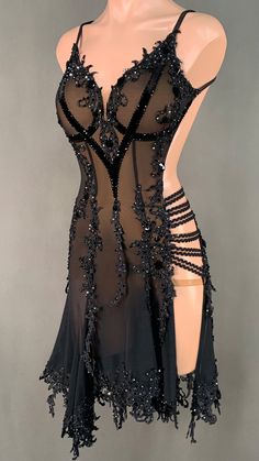 a mannequin wearing a black dress with sheer fabric and beads on the bust