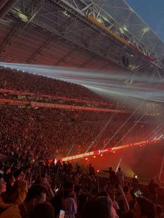 a stadium filled with lots of people watching something in the air and lights shining on the ground