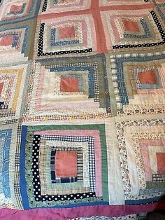 an old quilt is laying on top of a bed with pink and blue sheets,