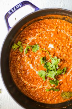 a pot filled with red beans and cilantro on top of a white table